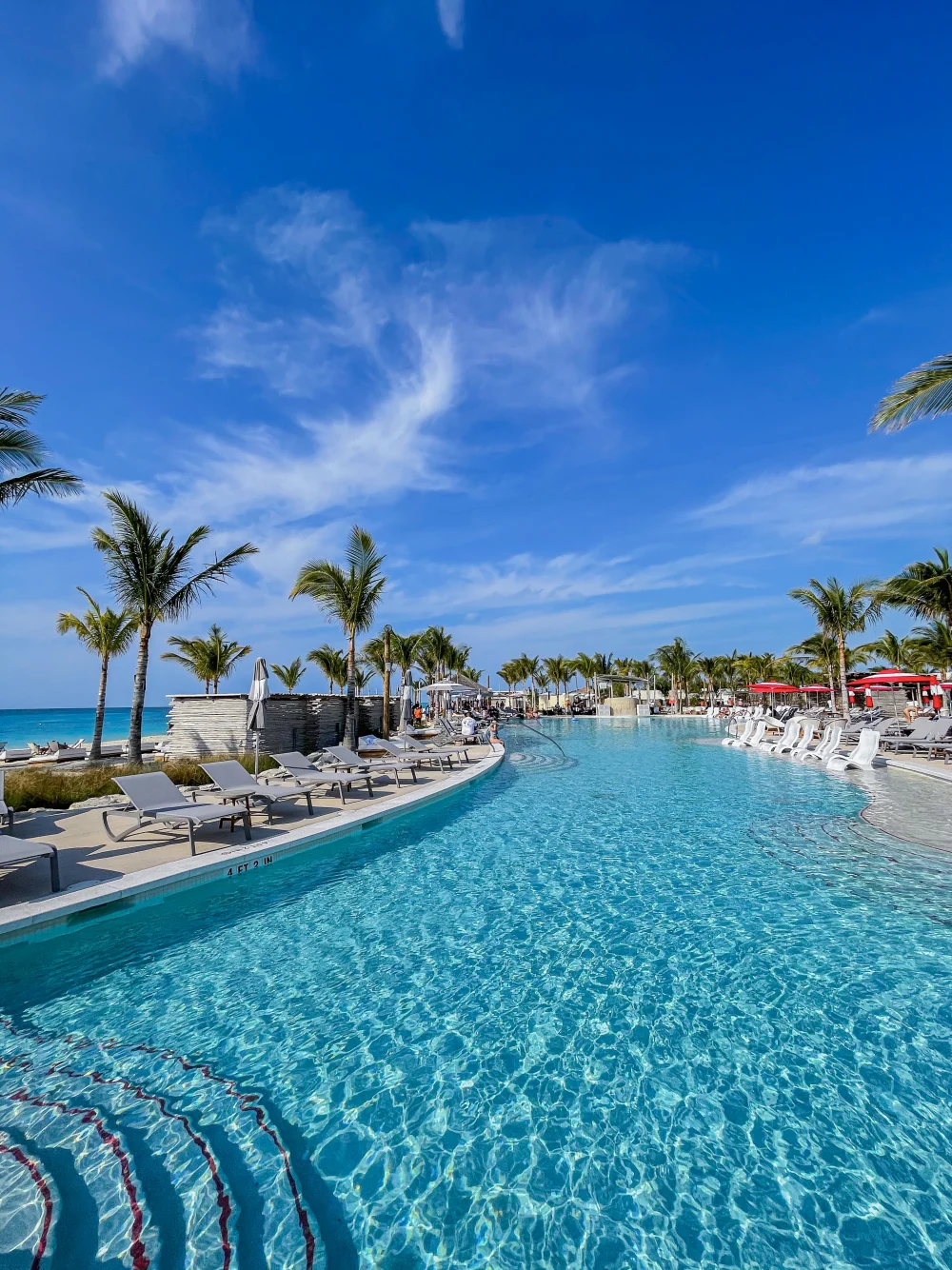 Virgin Voyages’ supplied photograph of the Beach Club at Bimini, with pale loungers in a turquoise pool beneath palms.