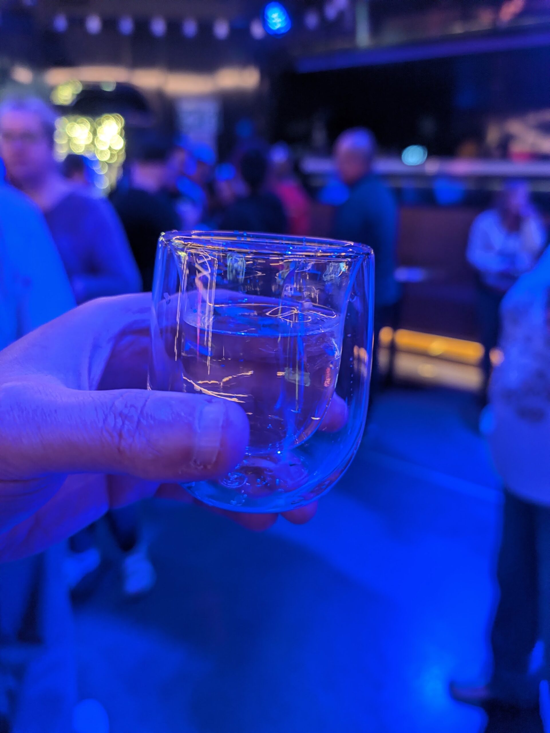 A clear Invisible Margarita in a double-walled glass, photographed by Cameron at the festival under blue lighting.